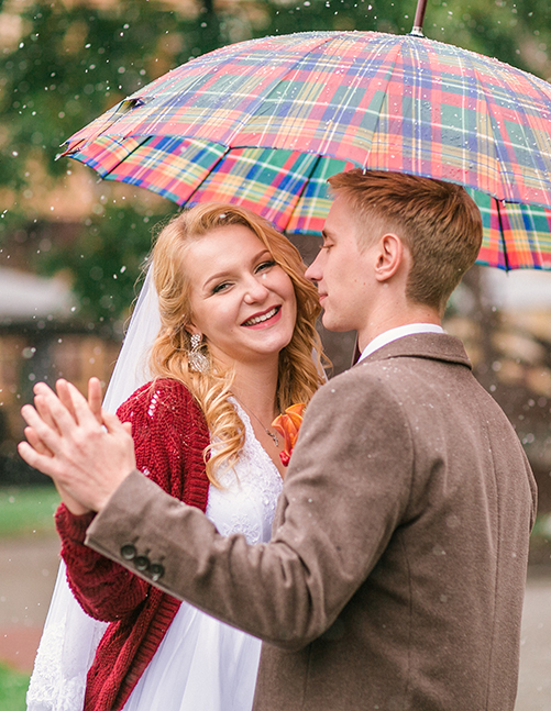 Young beautiful couple bride and groom in the snow with an umbre