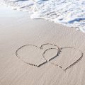 Two joined hearts traced into the sand at the seashore