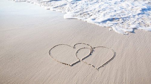 Two joined hearts traced into the sand at the seashore