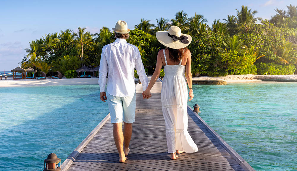 Newlywed couple walks down a wooden pier in a tropical location