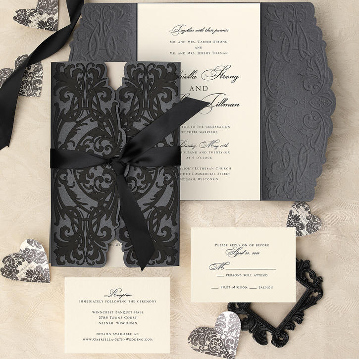 A black gatefold wedding invitation with black foil embossing on black shimmer paper is finished with a black satin bow and coordinating enclosure cards