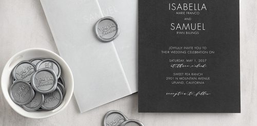 Contemporary wedding invitation featuring white ink printing on black paper show with a translucent wrap closed with a self-adhesive wax seal