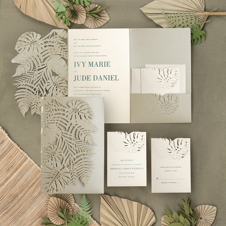 Large and luxurious pocket wedding invitation with a laser cut design featuring tropical greenery