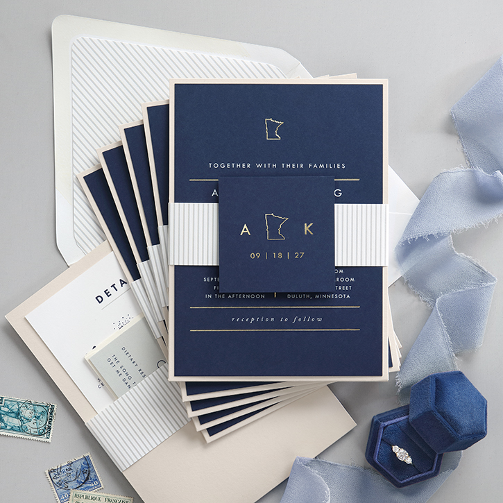 Contemporary wedding invitation ensemble featuring colored paper and a state icon stamped in gold foil.