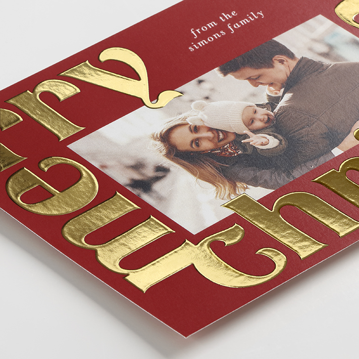 Holiday card featuring red and gold foil typography that arranges a wish for a merry Christmas into the shape of a Christmas tree.