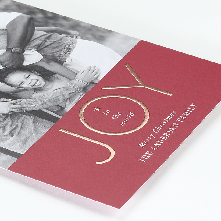 A photo holiday card is shown with "JOY" in enhanced raised foil above the personalization.