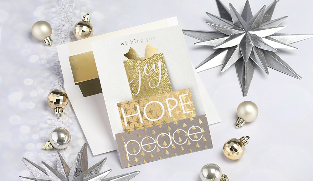 A die cut holiday card shaped like a gift with gold foil accents.