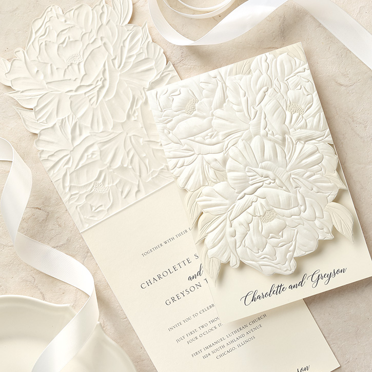 A luxurious wedding invitation with pearl embossed flowers on the top layer. 