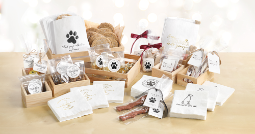 A group of pet wedding products laid out on a light wood table with pet wedding favors, napkins, and more.