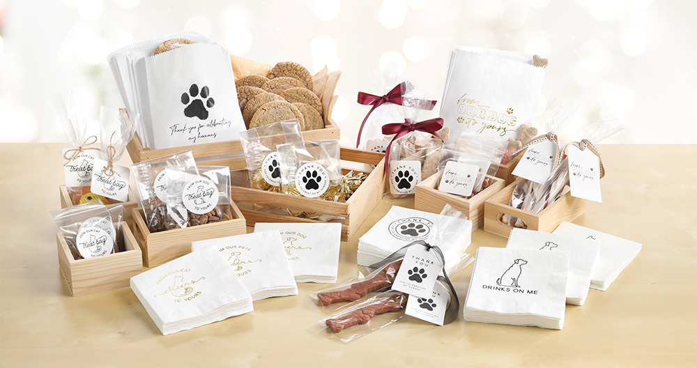 A group of pet wedding products laid out on a light wood table with pet wedding favors, napkins, and more.