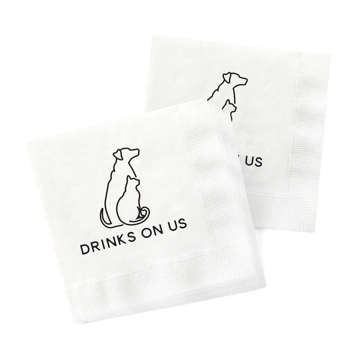 Wedding napkins with a cat and dog and the wording, "drinks on me".
